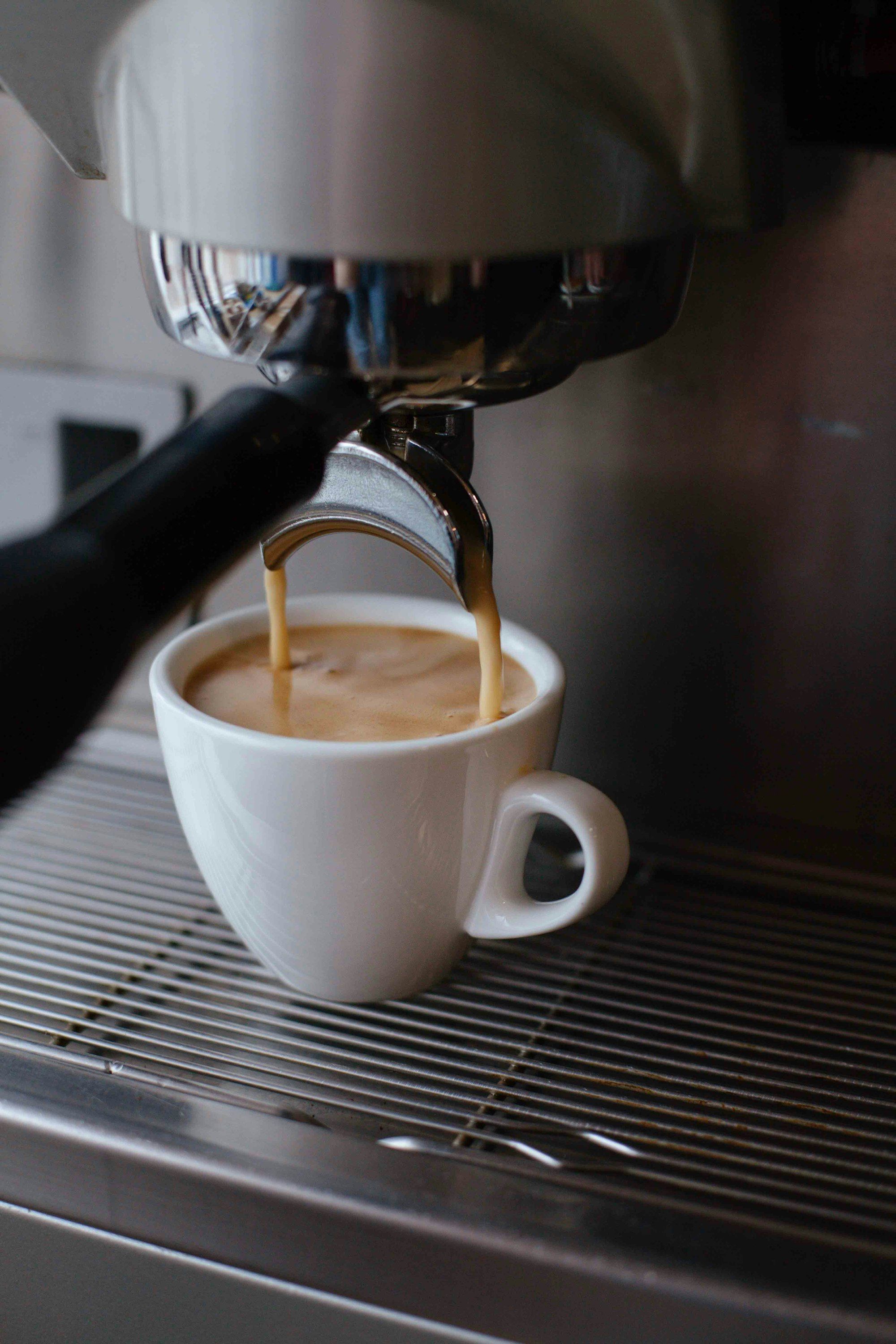Cangkir keramik putih berisi kopi di atas meja